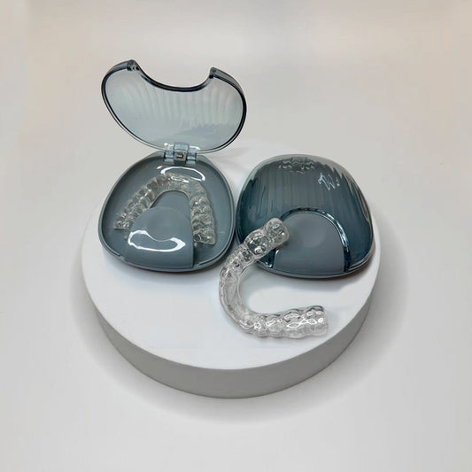 Two clear dental aligners in a gray case on a white background